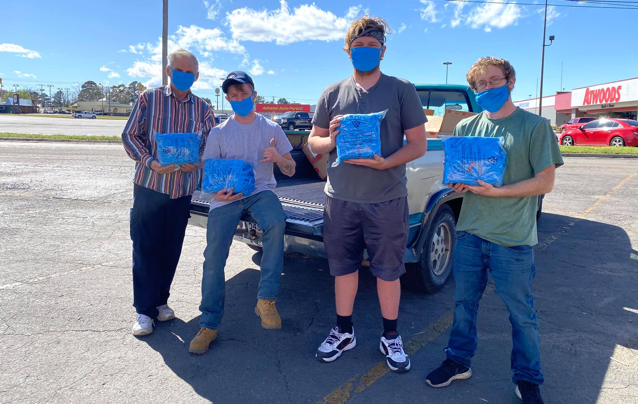 Four men pose with blue AT&T face masks.