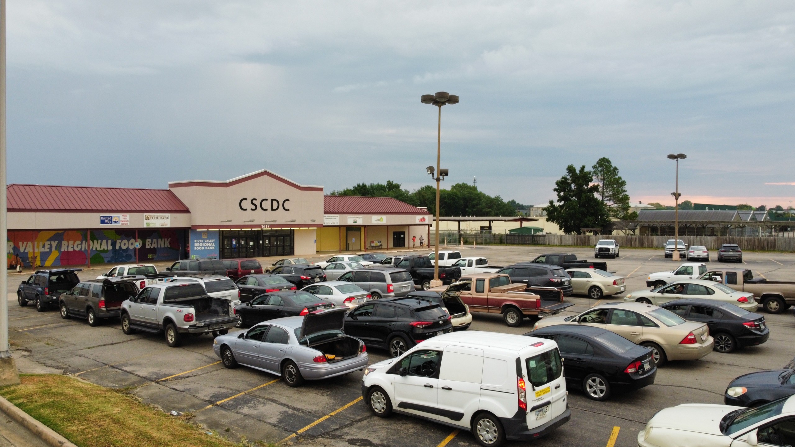 Rows of vehicles wait in line to receive food on an overcast day.